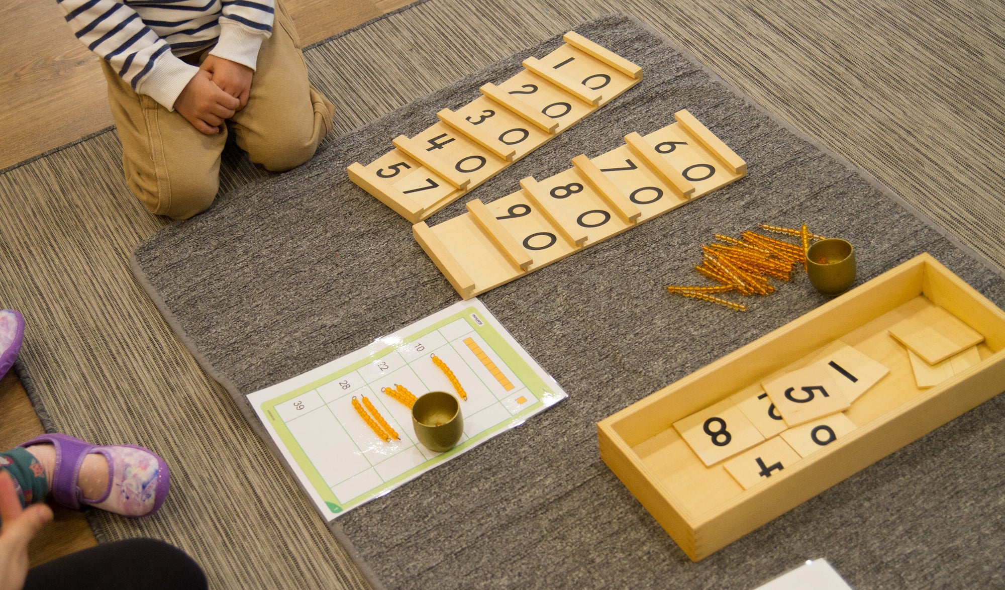 Niños y niñas participando en una presentación Montessori con material didáctico de matemáticas, aprendiendo conceptos numéricos de forma manipulativa.